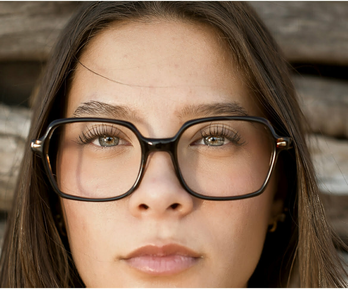 Jeune femme brune qui porte des lunettes en acétate chocolat. Elle a les yeux bleus.